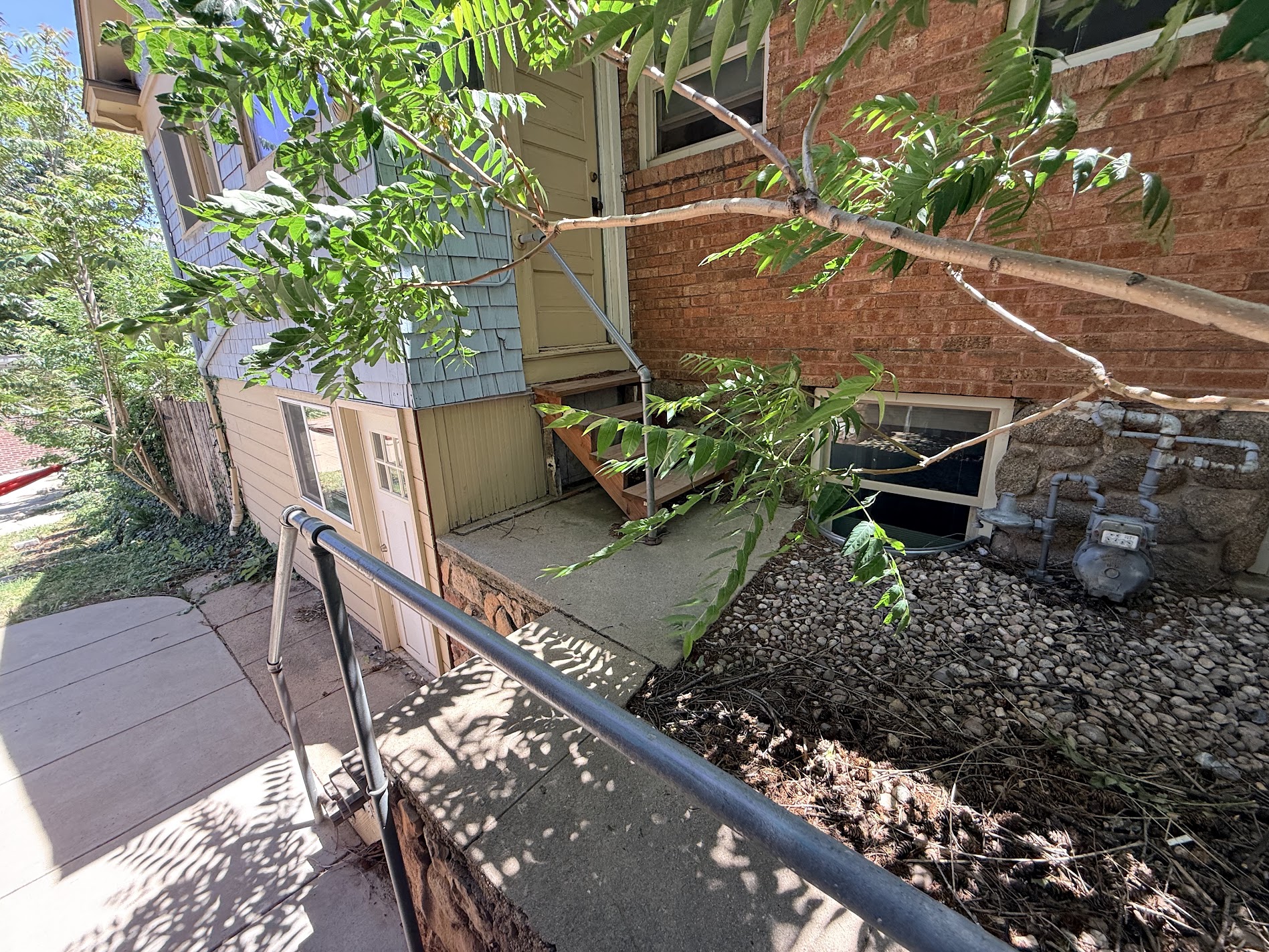 The side entrance of a brick house with a sage door and shingle siding