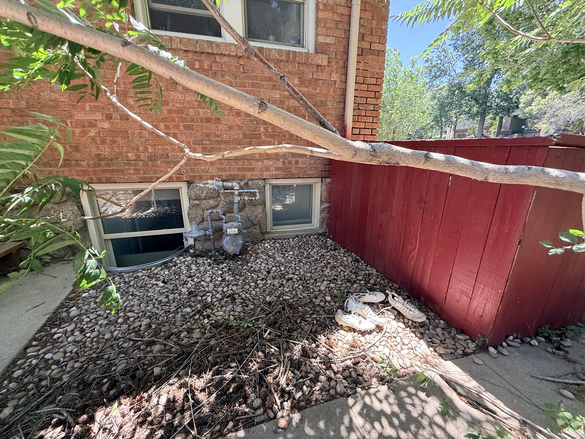 A brick foundation wall and basement windows beside a red painted fence