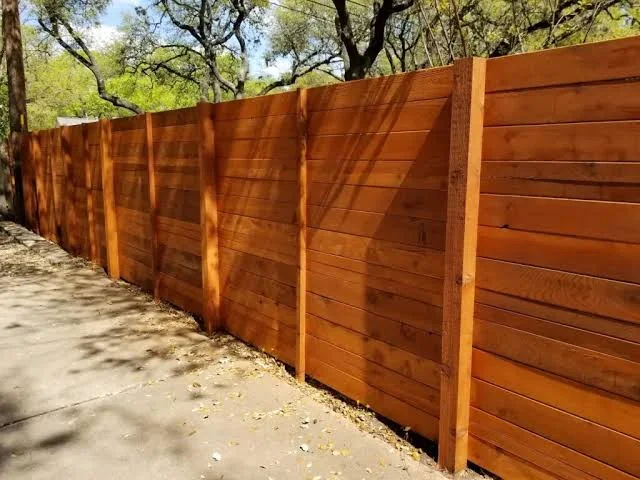 A freshly stained horizontal cedar privacy fence